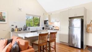 Enjoy cooking in this well-equipped kitchen with a central island, sink, and microwave, plus a large window offering a view of the surrounding greenery.