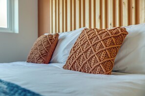 A bed with white bedding and two decorative pillows with a woven pattern. - Apt 4 - North Marine Villa - Modern apartment near North Bay Beach. (Scarborough)