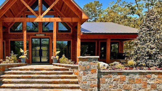 A lodge with a prominent wooden structure and stone steps leading to the entrance. - Pet-Friendly Playset Retreat for Families (Broken Bow)