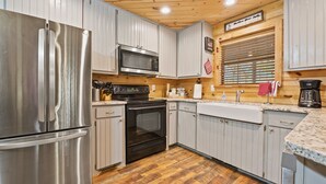 A modern kitchen with stainless steel appliances, wooden flooring, and light-colored cabinetry. - Pet-Friendly Playset Retreat for Families (Broken Bow)