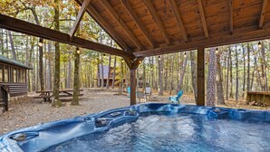 A hot tub under a wooden pavilion surrounded by trees. - Pet-Friendly Playset Retreat for Families (Broken Bow)
