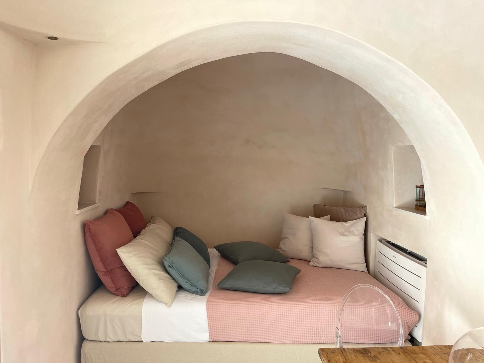 A cozy bedroom with a built-in bed, white walls, and an arched ceiling.
