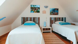 Ein Schlafzimmer mit zwei Betten, einem kleinen Nachttisch und Bildern an den Wänden.