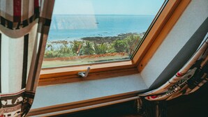 Ein Fenster mit Blick aufs Meer und ein Holztisch in einem Zimmer.
