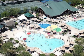 An aerial view of a resort with multiple swimming pools, sun loungers, and umbrellas.