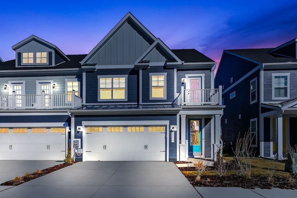 A modern two-story house with a garage, a balcony, and a well-maintained lawn.