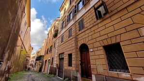 Una estrecha calle empedrada flanqueada por edificios históricos con ventanas y puertas arqueadas, evocando un ambiente tradicional europeo.