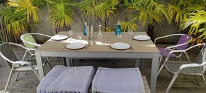 Un espace de restauration en plein air avec une table en bois prévue pour quatre personnes, entourée de chaises en métal.