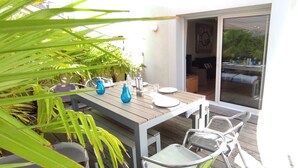 Un espace de restauration en plein air avec une table en bois, des chaises en métal et des vases en verre bleu.