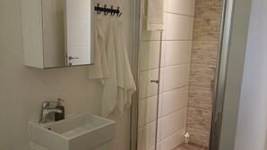 A modern bathroom with a white sink, mirror, and shower area.