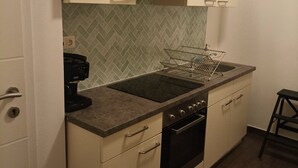 A compact kitchen with a gas stove, oven, and a coffee maker.