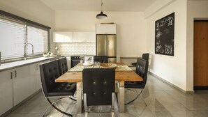 A modern kitchen with a wooden dining table, black chairs, and a stainless steel refrigerator. - Prime location Sunny 3bedroom apartment (Tel Aviv)