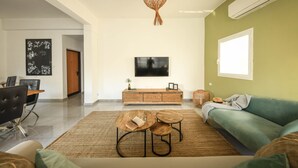 A modern living room with a sofa, coffee table, and TV. - Prime location Sunny 3bedroom apartment (Tel Aviv)