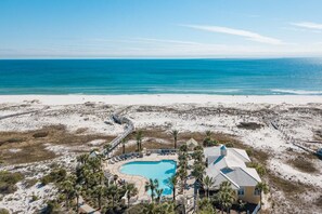A beachfront property with a swimming pool, palm trees, and a beach in the background. - La Brisa 201W- Inviting Large corner 3BR/3BA condo with a beautiful Gulf view (Gulf Shores)