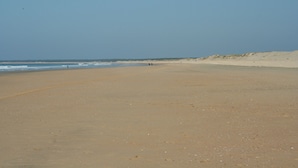 Une vaste plage de sable fin, avec des vagues douces et un ciel dégagé.