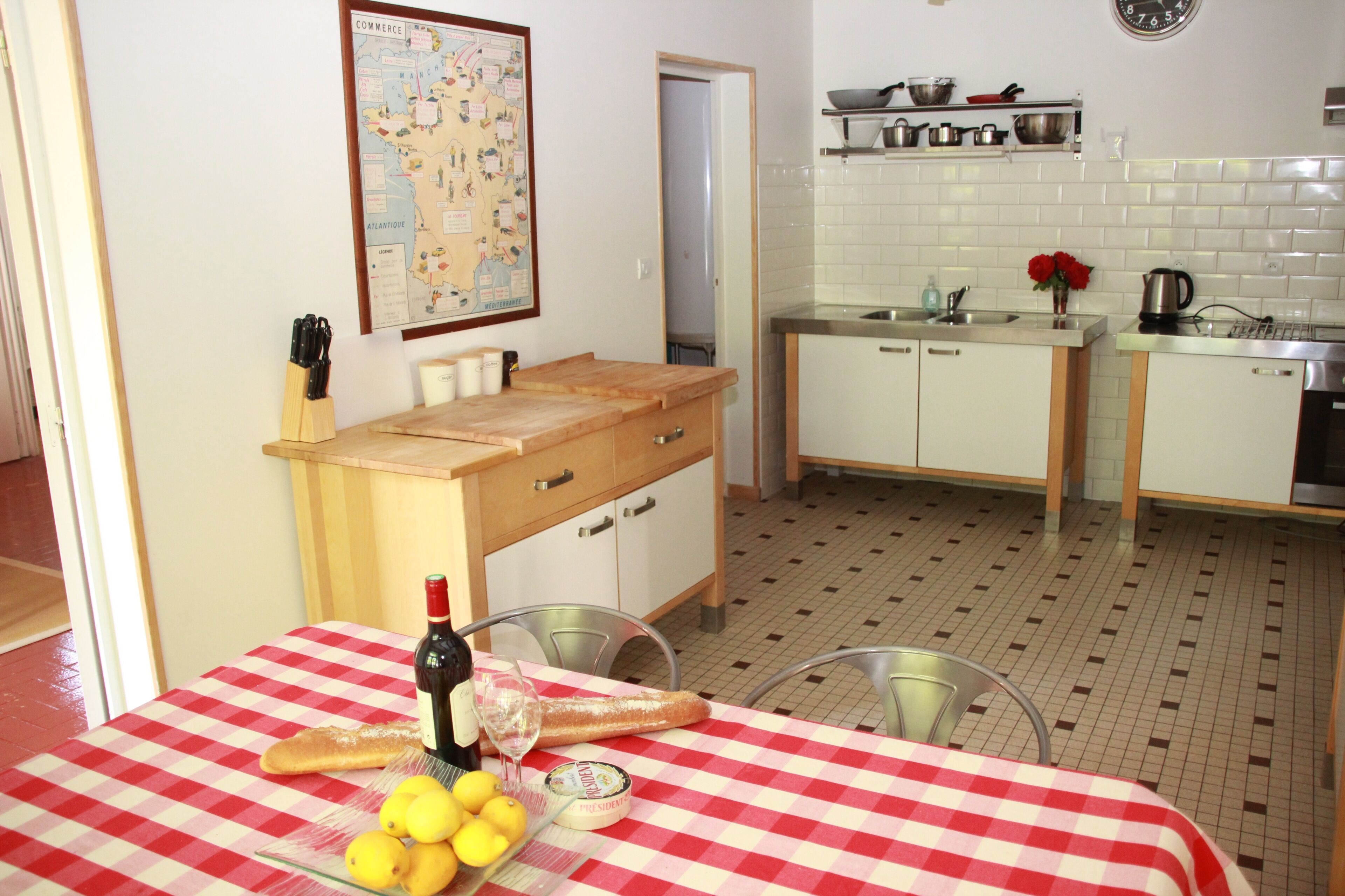 Une cuisine avec une table à manger dressée pour deux personnes, une carte accrochée au mur, ainsi qu’une variété d’ustensiles et d’appareils de cuisine.