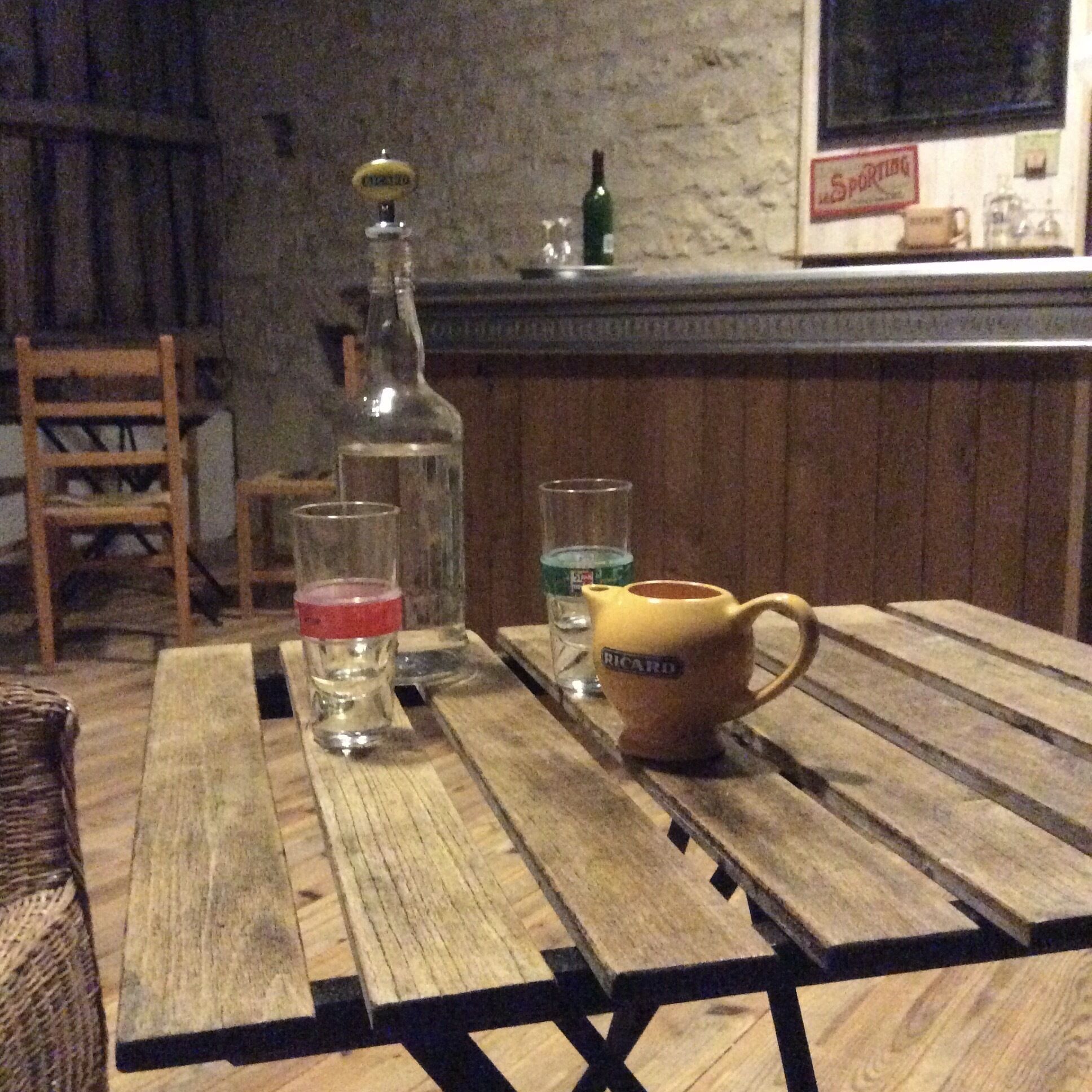 A wooden table with a bottle, glasses, and a mug.