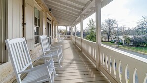 Un portico coperto con sedie di legno bianco e una ringhiera, con vista su una zona residenziale.
