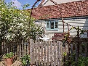 A wooden fence, a white table, and a bench in front of a house with a red-tiled roof. - The Bull Pen (Colyton)
