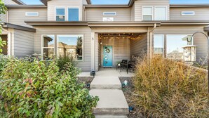 A modern two-story house with a front porch, a blue door, and a sign indicating the address. - Stylish Music-Inspired Retreat Near Old Town FC (Fort Collins)