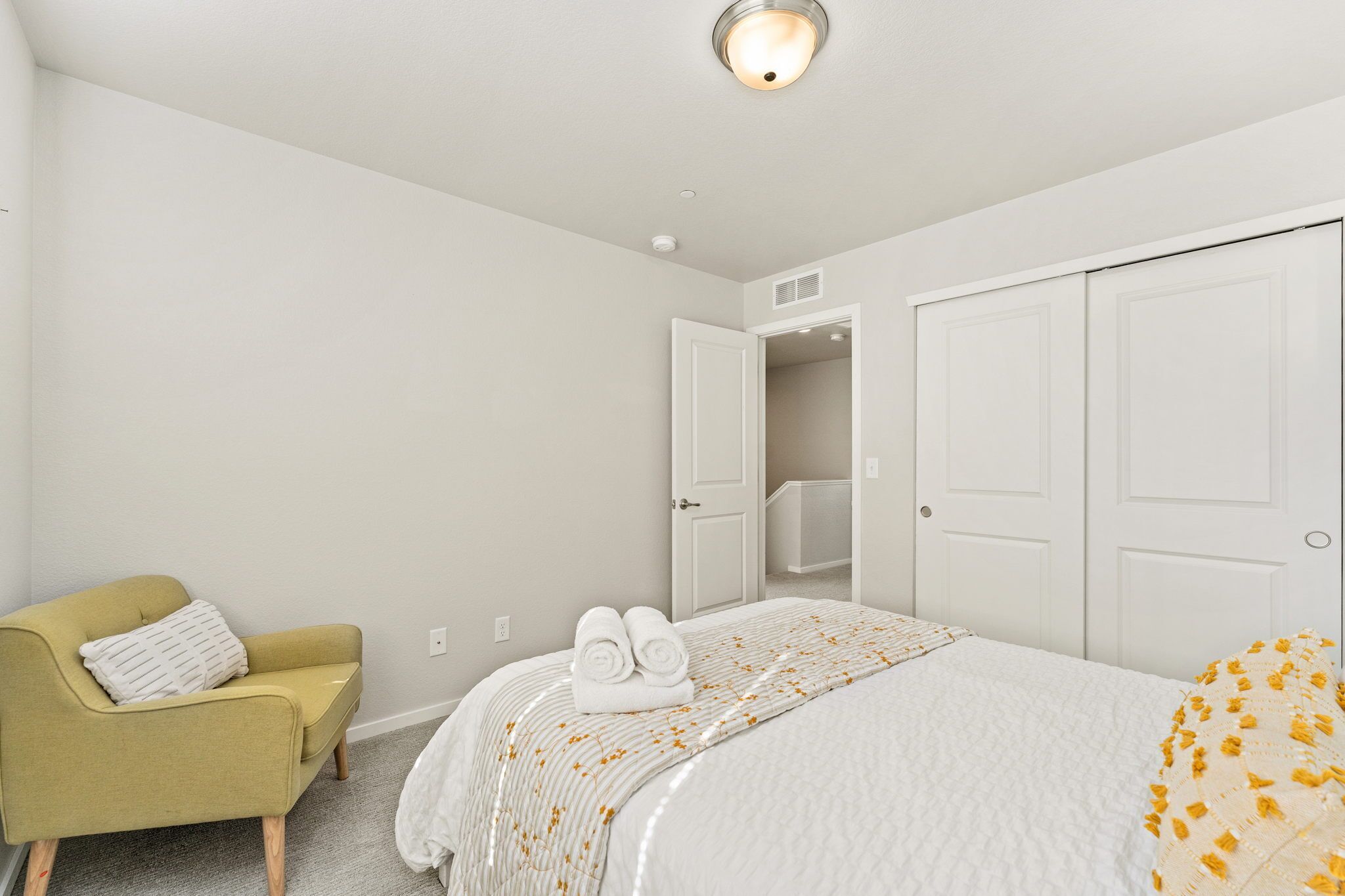 Un dormitorio con una cama, un sillón verde y un armario.