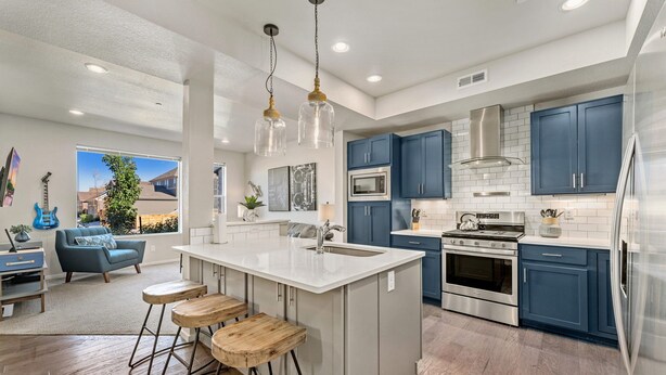 A modern kitchen with a central island, stainless steel appliances, and blue cabinets. - Stylish Music-Inspired Retreat Near Old Town FC (Fort Collins)