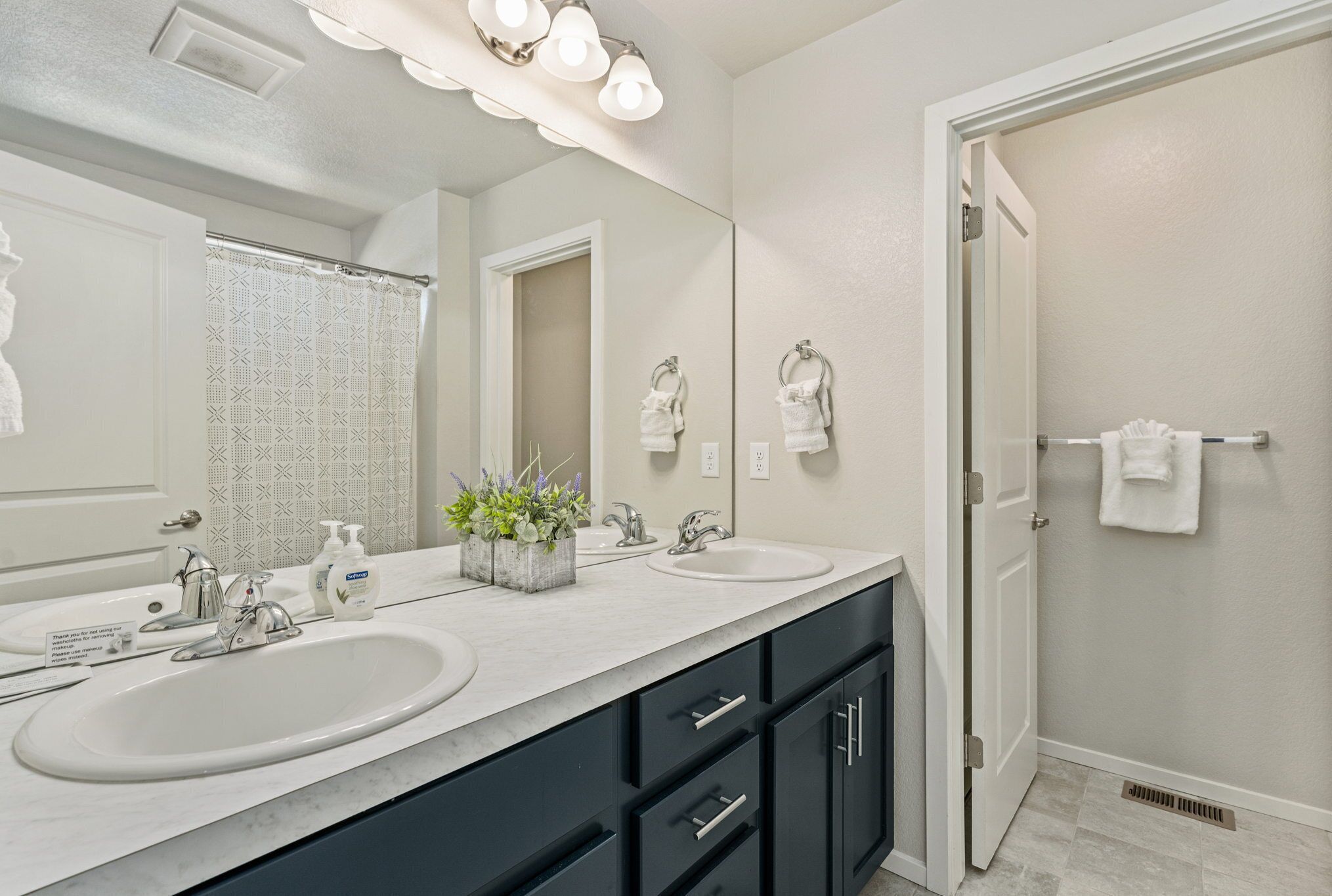 A bathroom with two sinks, a large mirror, and a shower area.