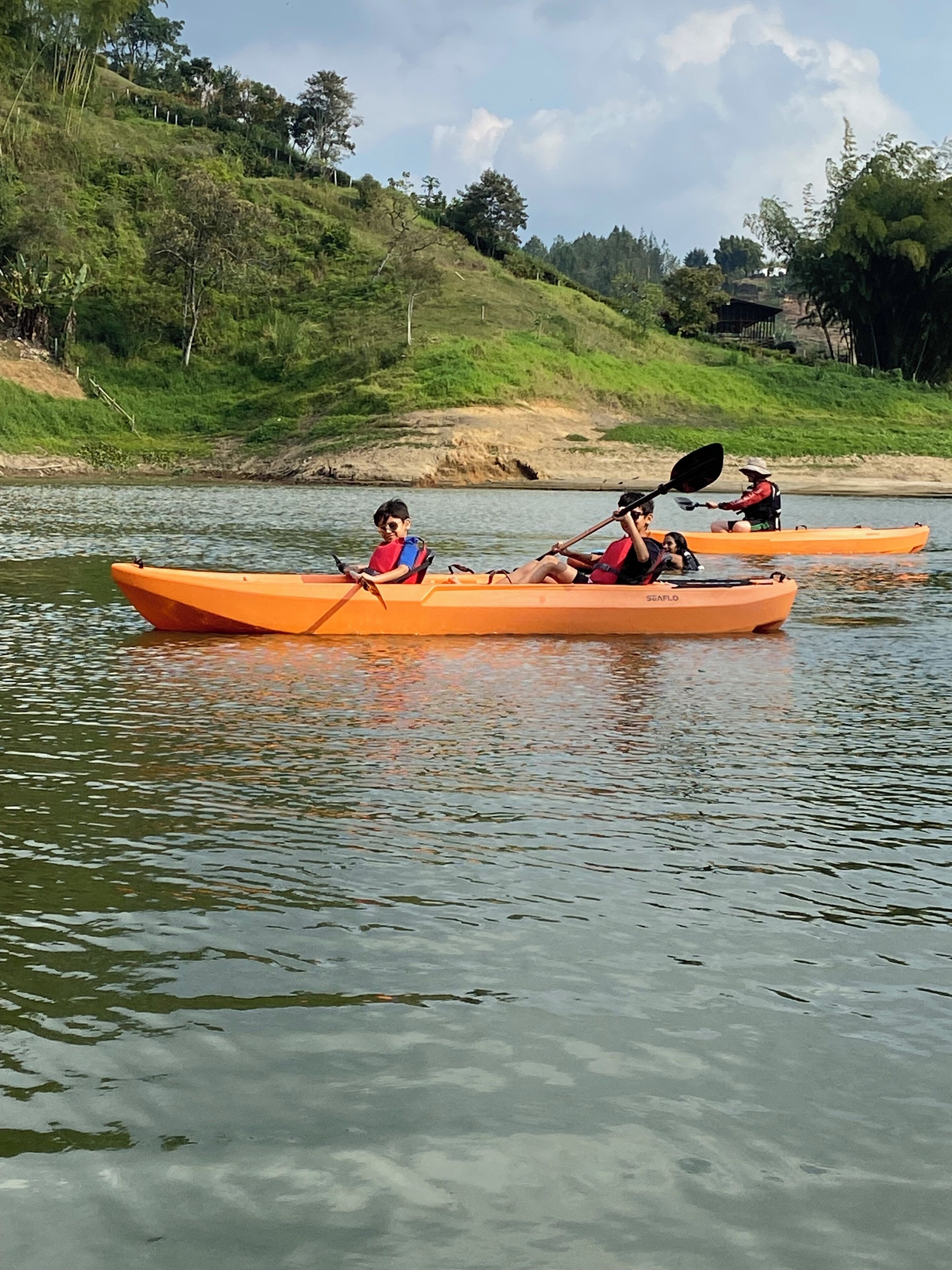 Two kayaks on a calm river with a hilly landscape in the background.