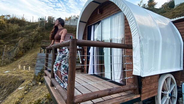 Een houten constructie met balkon, omgeven door begroeiing.