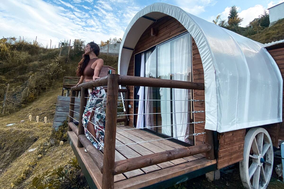 A covered wooden structure with a balcony, surrounded by natural vegetation.