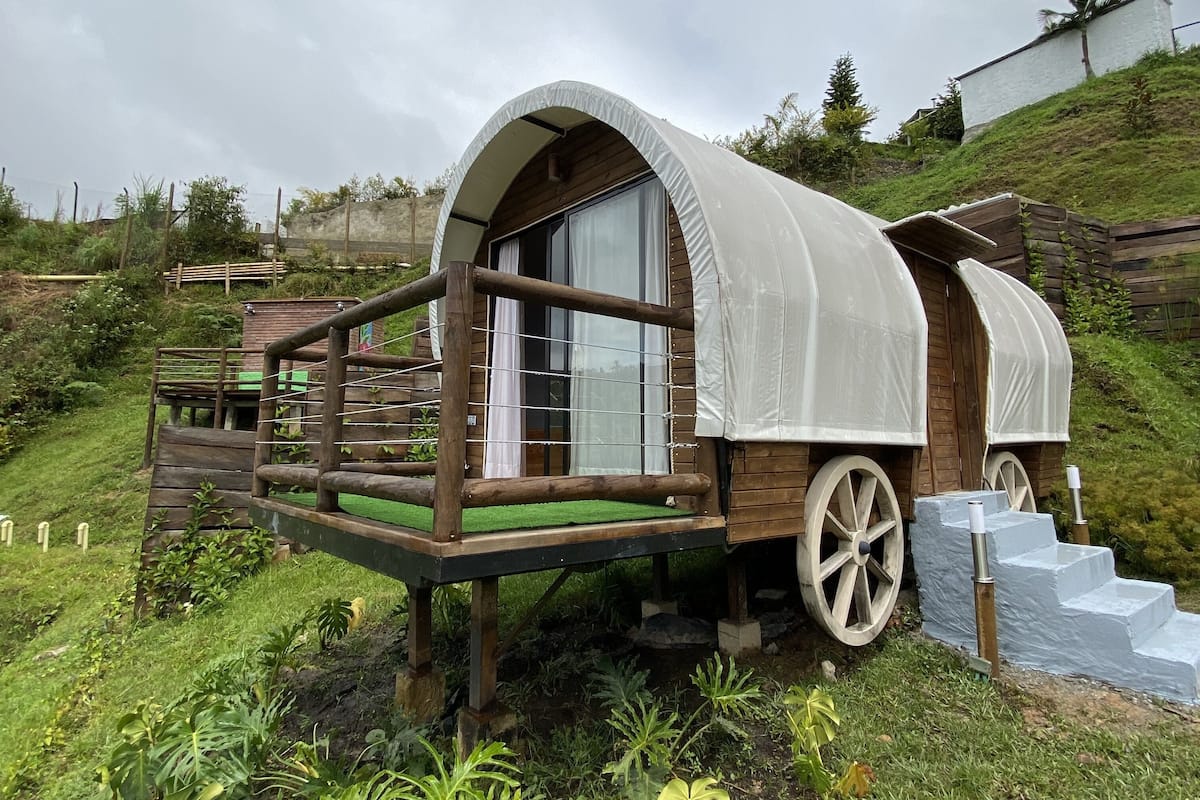 A wooden carriage with a covered roof and a wooden deck, surrounded by greenery.