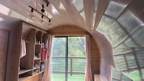 Ruime kamer met houten wanden, een grote schuifdeur naar een balkon en een plafond met een uniek, gebogen ontwerp.