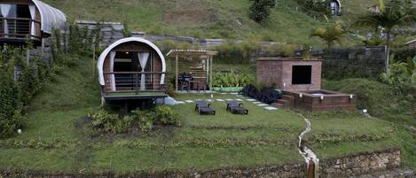 A hillside property with a covered outdoor seating area, a small brick structure, and a pool.