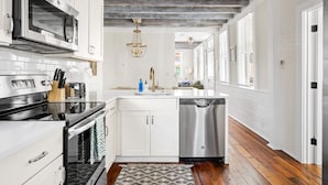 A modern kitchen with white cabinetry, stainless steel appliances, and a wooden floor. - Historic Downtown Home - Luxury Stay On St Philip (Charleston)