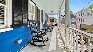 A porch with rocking chairs, a white railing, and a blue exterior wall. - Historic Downtown Home - Luxury Stay On St Philip (Charleston)