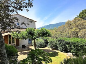 A house with a patio, surrounded by greenery and a mountain in the background. - 2 3* POOL VILLAS WITH PANORAMIC VIEWS BETWEEN THE SEA AND THE MOUNTAINS (Porto-Vecchio)