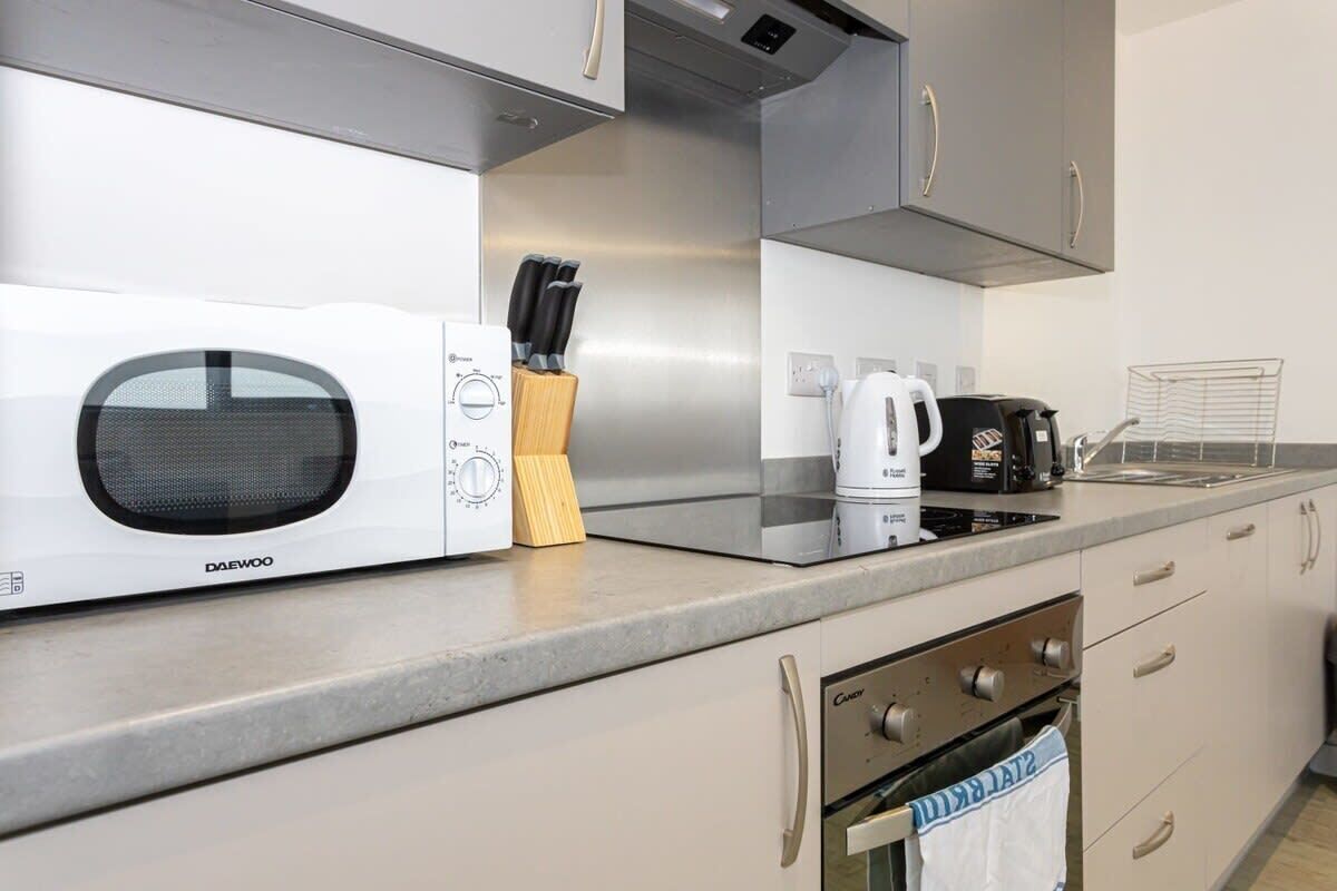 Een moderne keuken met een ingebouwde magnetron, koffiezetapparaat en roestvrijstalen apparatuur.