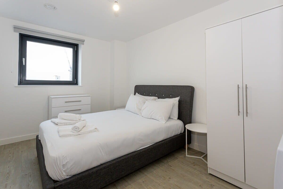 Een slaapkamer met een bed, nachtkastje, kast en raam.