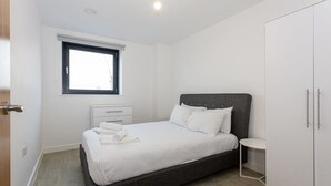 Une chambre à coucher avec un lit, une table de chevet, une armoire et une fenêtre.