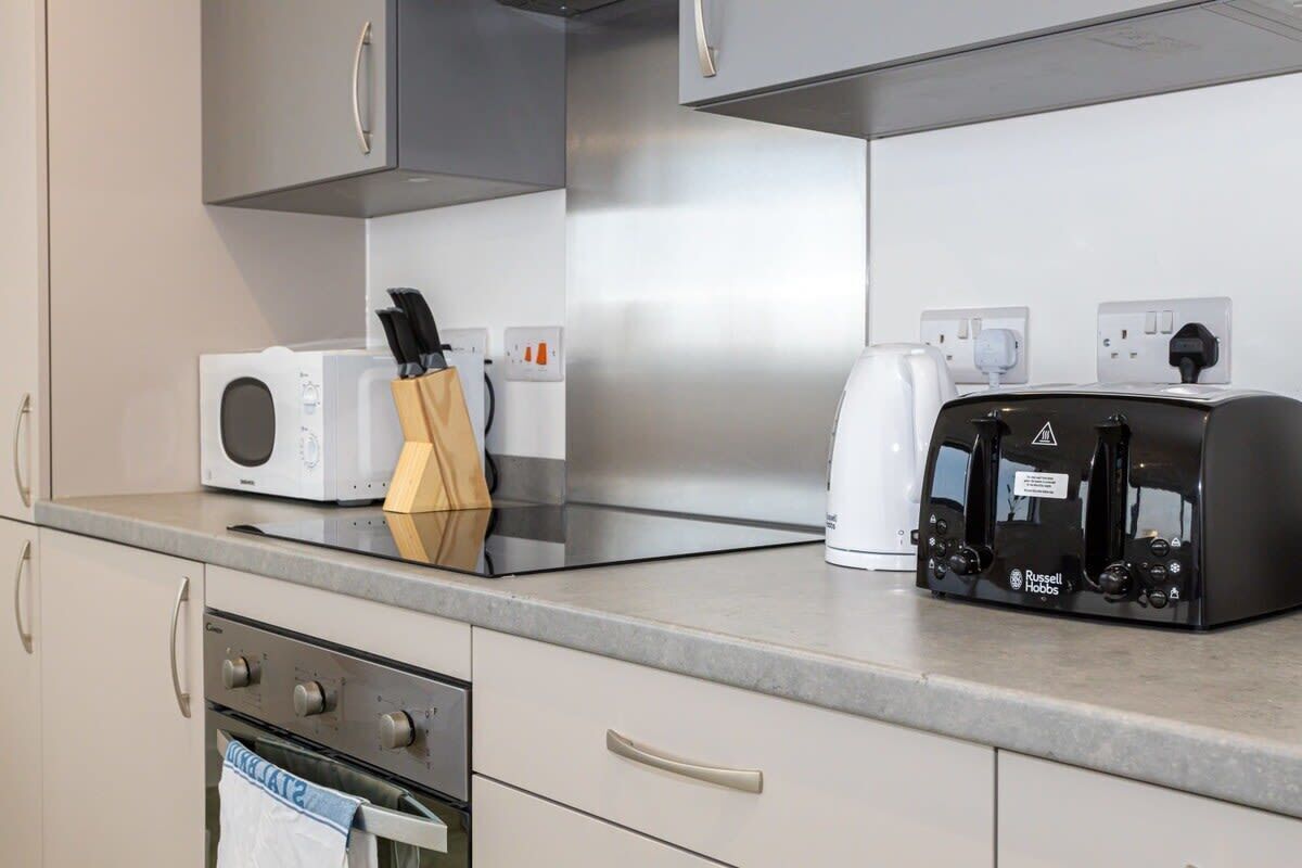 A modern kitchen with a microwave, toaster, and oven. There are cabinets and a countertop.