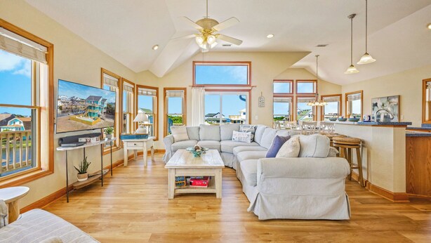 A spacious living room with a large sofa, a coffee table, and a TV. There are multiple windows providing views of the outside. - Canalfront Home with Private Pool, Hot Tub, Private Boat Dock, Game Room (Frisco)