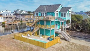A multi-level waterfront property with a pool, wooden deck, and multiple balconies. - Canalfront Home with Private Pool, Hot Tub, Private Boat Dock, Game Room (Frisco)