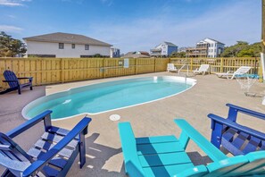 Ein Garten mit Pool, blauen Liegestühlen und einem Holzzaun.