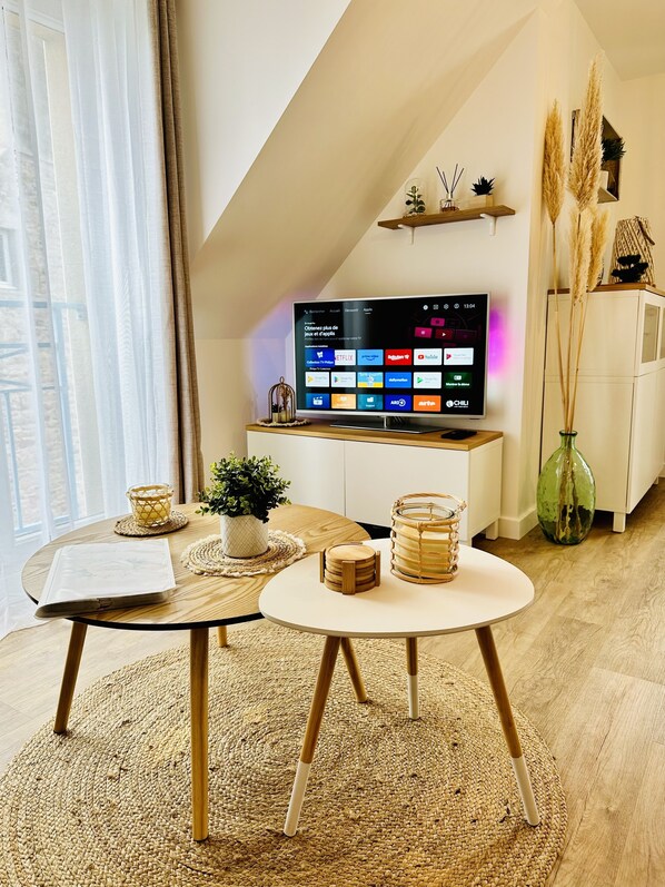 Ein modernes Wohnzimmer mit einem an der geneigten Decke befestigten Fernseher, einem Holztisch, einem runden Tisch und einem gewebten Teppich.