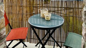 A balcony with a round table, two chairs, and a bamboo fence. - The roofs of Nazado (2/4 people) (Erquy)