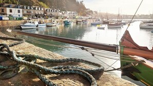A harbor with boats docked, a rocky shore, and buildings in the background. - The roofs of Nazado (2/4 people) (Erquy)
