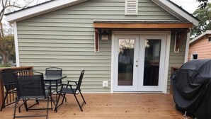 Une terrasse avec une table et des chaises, une porte-fenêtre coulissante et un barbecue abrité.