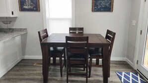 Un espace repas comprenant une table rectangulaire et six chaises, un ventilateur de plafond et deux tableaux accrochés au mur.
