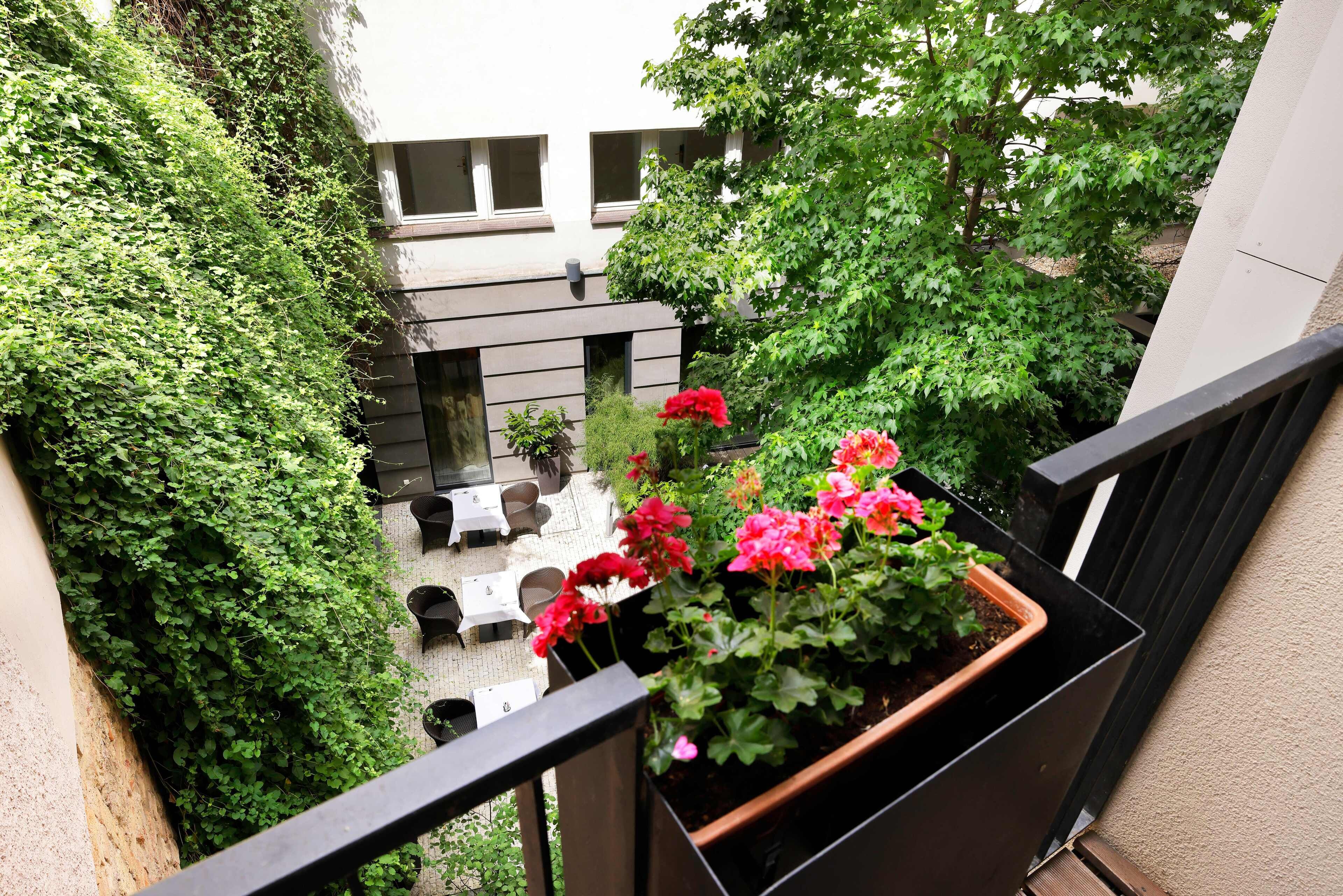 Un balcón con vista a un patio, mobiliario exterior y plantas en macetas.