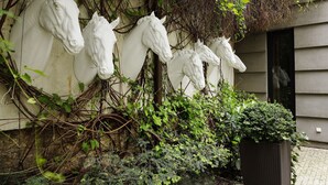 Un mur orné de sculptures de chevaux et envahi par la végétation.